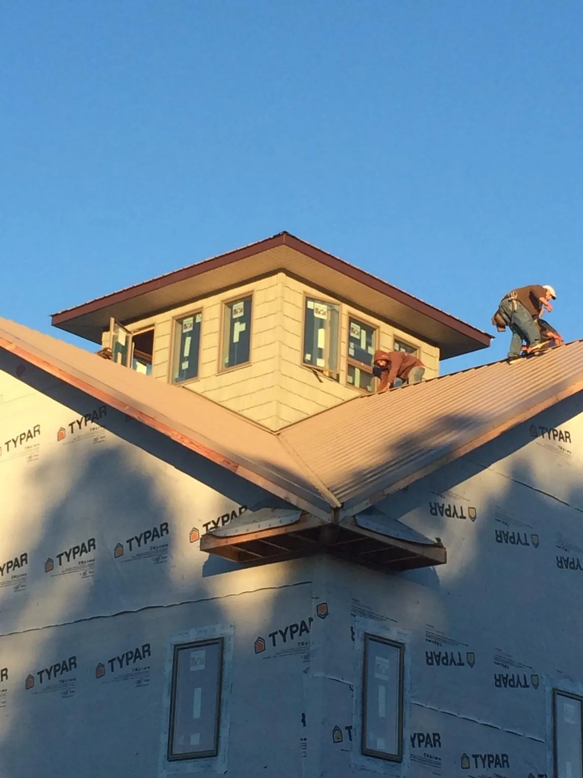 Roofers working around a rooftop cupola on a new metal roof at sunset — Roof Waterproofing in Freedom by Roofing Brothers